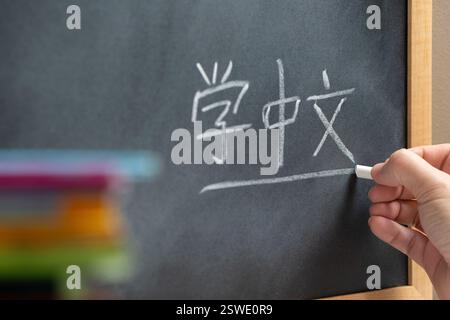 Handschrift auf einer Tafel in einem Chinesischen Sprachkurs mit dem Wort „Learn Mandarin“ darauf. Einige Bücher und Schulmaterialien. Stockfoto