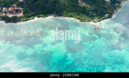 Eine ruhige Bucht mit kristallklarem türkisfarbenem Wasser, umgeben von dichtem Wald und Sandstränden. Praslin, Seychellen. Stockfoto