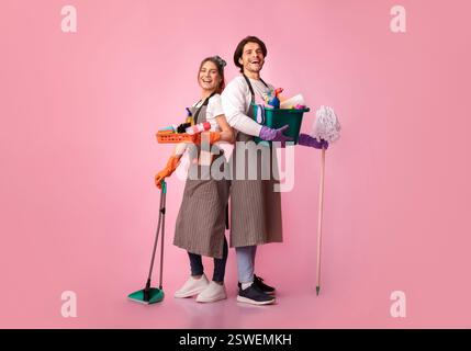 Glückliches junges Paar mit vielen Waschmitteln, die über rosafarbenem Hintergrund posieren Stockfoto