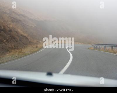 Nebelige Autobahn. Blick vom Fahrer des Autos. Leere Morgenstraße in dichtem Nebel. Straße durch dichten Nebel. Stockfoto
