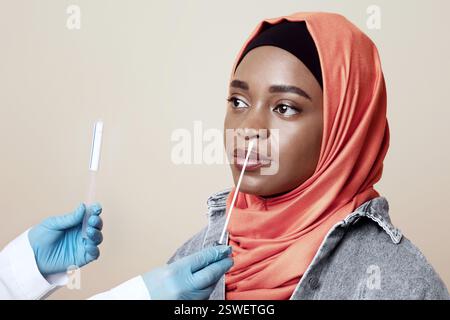 Medizinisches Personal, das einen Tupfer für eine Coronavirus-Probe von einer muslimischen Frau nahm Stockfoto