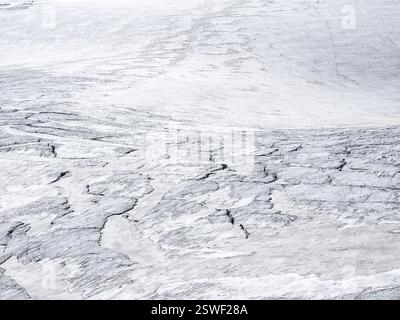 Die Textur von weißem Schnee, weißem Hell-Dunkel. Minimaler natürlicher Hintergrund der eisigen Wand mit Rissen und Kratzern von Eis vom Gletscher Stockfoto