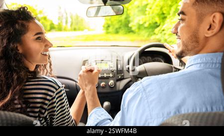 Liebevolles Paar, das die Hände hält, während es im Auto sitzt, Rückansicht Stockfoto