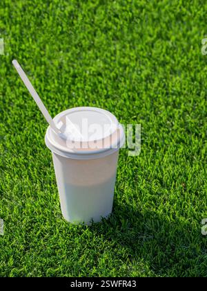 Trinken Sie in einem Papierbecher mit Trinkhalmen auf dem Fußballfeld. Stockfoto