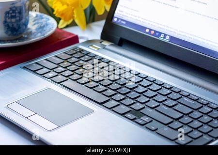 Seitenansicht des offenen Laptops mit weißem Bildschirm auf dem Schreibtisch. Online-Arbeit im Geschäft oder zu Hause. Stockfoto