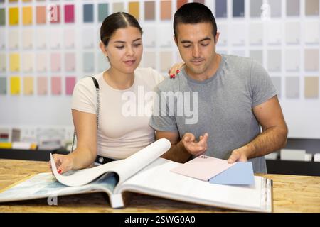 Ein Ehepaar wählt die Farbe der Keramikfliesen aus dem Katalog im Baumarkt Stockfoto