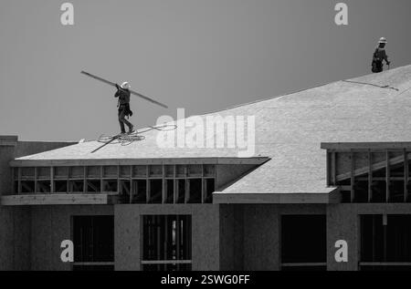Dachüberdachung auf dem Dach. Dachbauer installieren neues Dach. Bauarbeiter, die eine große Dachwohnung überdacht haben. Zimmermann Stockfoto