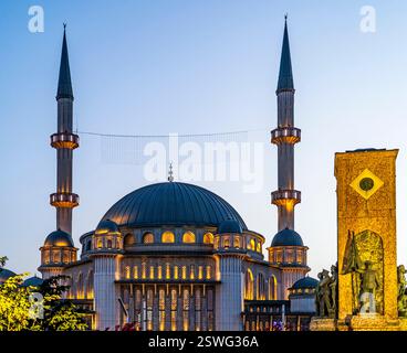 Ein atemberaubender Blick auf eine große Moschee in der Abenddämmerung mit zwei hohen Minaretten und einer großen Kuppel. Die Moschee ist mit warmen Lichtern beleuchtet, was eine ruhige Atmosphäre schafft Stockfoto