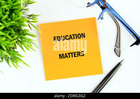 Ein hellgelber Haftnotiz mit der Aufschrift „Education Matters“ (Bildungsangelegenheiten) wird neben einer Brille und einem Stift platziert, um die Bedeutung des Lernens in Wirtschaft und Finanzen zu unterstreichen Stockfoto