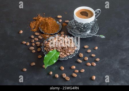Tasse Kaffee und Kaffeebohnen mit gemahlenem Pulver auf schwarzem Hintergrund Stockfoto
