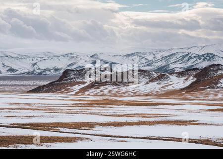 Pastellfarben mit den schneebedeckten Bergen in der Ferne. Malerische, minimalistische Landschaft mit Felsen in Pastelltönen. Schneepad Stockfoto