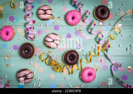 Donuts, Berliner, Krapfen mit Bändern und Konfetti. Farbenfrohes Bild von Karneval, Geburtstag und fasching, grüner Hintergrund, Draufsicht Stockfoto