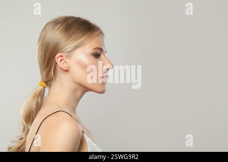 Schönes junges blondes weibliches Modell mit klarer Haut, weichem Make-up und gesundem Haar und natürlichem emotionalem Ausdruck Porträt aufgenommen. Profil des blonden Arbeitsbereichs Stockfoto