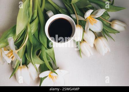 Eine Tasse Kaffee, ein offenes Buch und ein Blumenstrauß auf der Holzplatte. Flache Ausführung mit Draufsicht. Kopierbereich. Stockfoto
