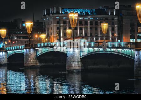 Nachtlichter auf der Brücke nach St. Petersburg. Abendbeleuchtung der Stadt. Stockfoto
