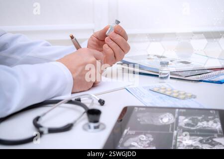Ein medizinisches Fachpersonal macht sich Notizen und überprüft Medikamente, während er an einem Schreibtisch in einer klinischen Umgebung sitzt und sich auf die Patientenversorgung konzentriert. Stockfoto