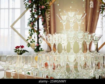 Nahaufnahme leerer Weingläser auf einem Tisch ist eine Pyramide. Wunderschöne Hochzeitszeremonie drinnen. Stockfoto
