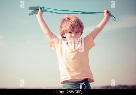 Gesundheit fröhlich Kind Lebensstil. Springseil, süßer Junge, der an einem Springseil arbeitet. Süßes Kind, das Sport auf blauem Himmel übt. Stockfoto