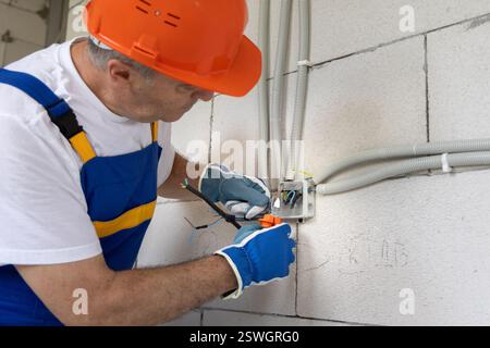 Elektroingenieur des Bauherstellers, der alle Kabel gemäß dem Projekt der Elektroinstallation eines neuen Hauses verbindet Stockfoto