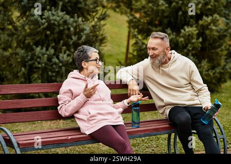 Ein liebevolles Paar teilt freudige Momente, während es auf einer Bank in einer ruhigen Parklandschaft sitzt. Stockfoto
