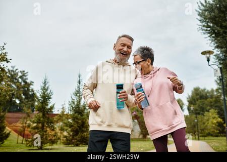 Ein liebevolles Paar teilt einen freudigen Moment, während sie Hand in Hand durch einen üppigen Park schlendern. Stockfoto