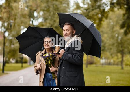 Ein liebevolles Paar geht Hand in Hand unter Sonnenschirmen und lächelt, während sie warme Getränke teilen. Stockfoto