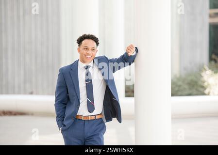 Geschäftsmann lächelt und lehnt sich an die Stange Stockfoto