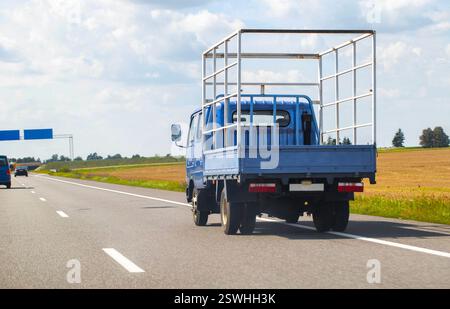 Ein offener Tieflader fährt im Sommer auf einer Autobahn. Transport von Gütern bis zu 5 Tonnen. Vermietung von Lkw für den regionalen und internationalen Transport Stockfoto