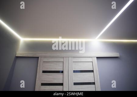 Schöne moderne, dehnbare Decke mit gelben LED-Linien um den Rand. Stilvolle Designer-Decke im Flur, Dekoration Stockfoto