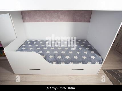 Ein Etagenbett mit Leiter in einem modernen Kinderzimmer mit weißen Möbeln und Innenausstattung. Stockfoto