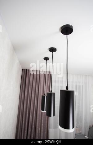 Moderne Pendelleuchten mit schwarzer Diode an einer weißen Stretchdecke, Designer. Stockfoto