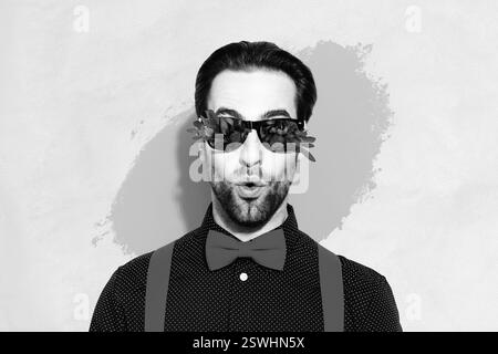 Composite-Collage-Bild einer eingefärbten schwarzweißen Gamma-Person mit gegossener Lippenblumen-Sonnenbrille, isoliert auf lackiertem Hintergrund Stockfoto
