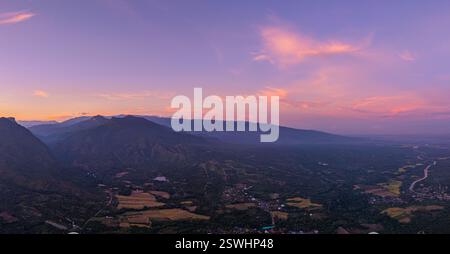 Ein atemberaubender Blick auf einen farbenfrohen Sonnenuntergang über mehrschichtigen Bergsilhouetten mit warmen Orange-, Rosa- und Blautönen, die sich nahtlos über die SK vermischen Stockfoto