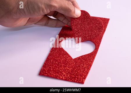 Rote Herzschablone aus dem roten Glitzerblatt mit weißem Hintergrund Stockfoto