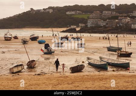 Blick hinunter auf Harbour Beach, St Ives, Cornwall, England Großbritannien, zu den Booten, die bei Ebbe mit Angeln, kleinen Schiffen und Immobilien am Meer ankern Stockfoto