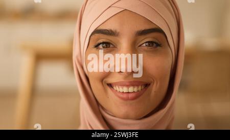 Glückliches zahniges Lächeln mit Gesundheit weißen Zähnen sorglose Arabische Frau Blick in die Kamera zu Hause Büro Portrait islamische Dame muslimische indische Mädchen weiblich Stockfoto
