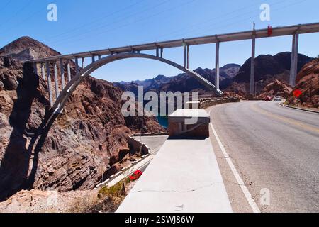 Die Brücke überspannt einen Fluss und ist von Bergen umgeben. Die Brücke ist ein großer Bogen und liegt an einer Straße Stockfoto