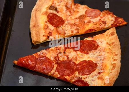 Zwei Scheiben frisch gekochter Pizza auf einem Backblech. Fastfood. Stockfoto