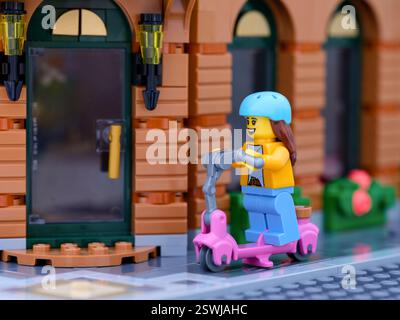 Tambow, Russische Föderation - 30. Juni 2024 Lego Girl Minifigur, die auf einem Roller eine Stadtstraße hinunterfährt Stockfoto