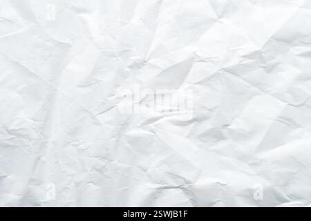 Strukturierter, zerknitterter weißer Papierhintergrund mit Falten und Falten. Stockfoto