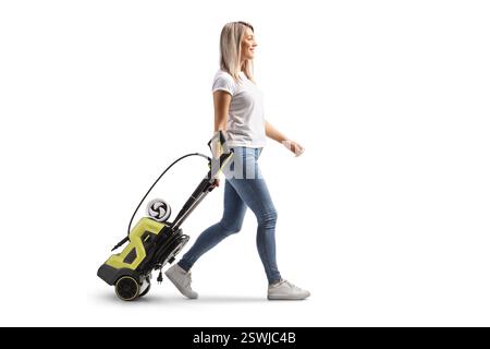 Junge Frau, die eine Hochdruckreiniger-Maschine auf weißem Hintergrund zieht Stockfoto