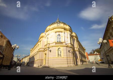 Majestätische architektonische Struktur mit gelben und rosafarbenen Details, neoklassizistischem Stil und Skulpturen, unter einem dynamischen Himmel, der von Fl dominiert wird Stockfoto
