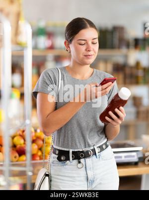 Frau, die ein Paket Ketchup scannt Stockfoto