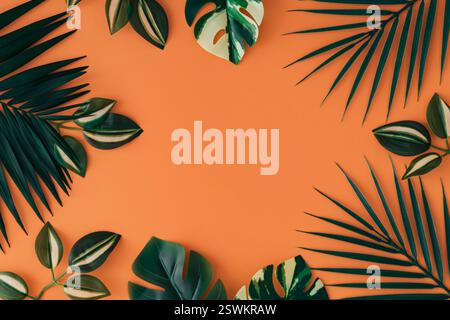 Bunte tropische Blätter auf pastellorangen Hintergrund. Minimales sommerliches Exotik-Konzept mit Kopierraum. Kreatives Design. Grenzanordnung. Stockfoto