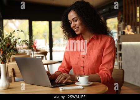 Frau, die am Laptop am Tisch im Café arbeitet Stockfoto