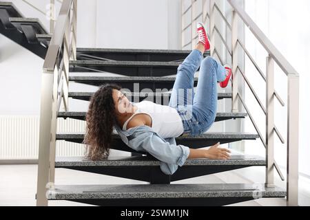 Verletzte Frau auf Treppen im Gebäude nach dem Sturz. Gefährlicher Unfall Stockfoto