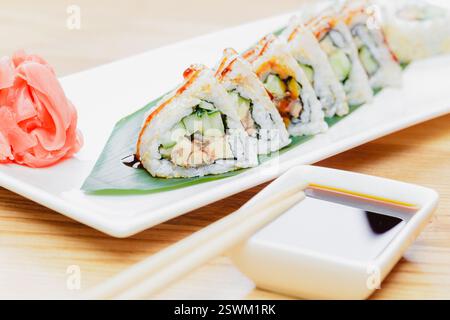 Genießen Sie eine wunderschön zubereitete Sushi-Platte mit frischen Zutaten und Dippsoße auf einem Holztisch Stockfoto