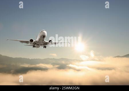 Das Flugzeug fliegt am sonnigen Morgen über Berge Stockfoto