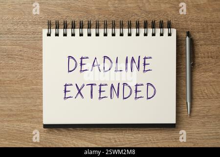 Text Deadline verlängert in Notizbuch und Stift auf Holztisch, Draufsicht Stockfoto