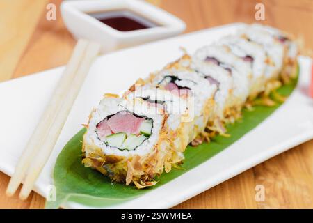 Frisch zubereitetes Sushi auf einem weißen Teller mit Saucen und Essstäbchen, bereit für ein köstliches Essen Stockfoto